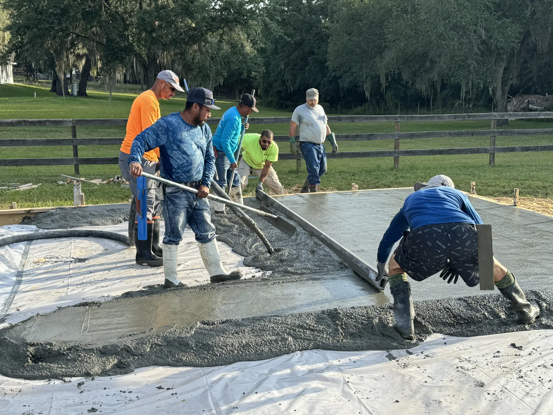 Concrete crew pouring and leveling a foundation slab with hand tools