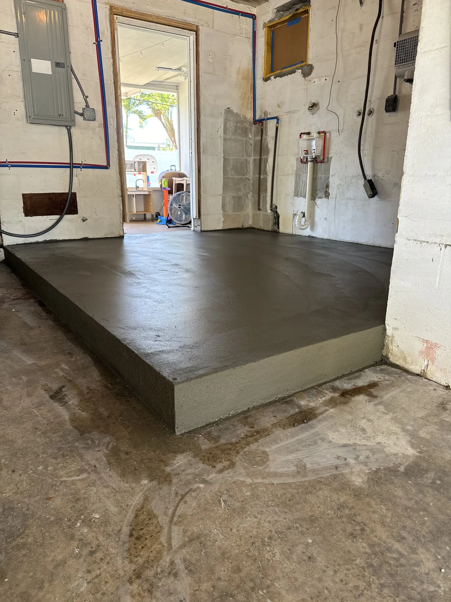 Freshly poured raised concrete pad inside an interior utility room