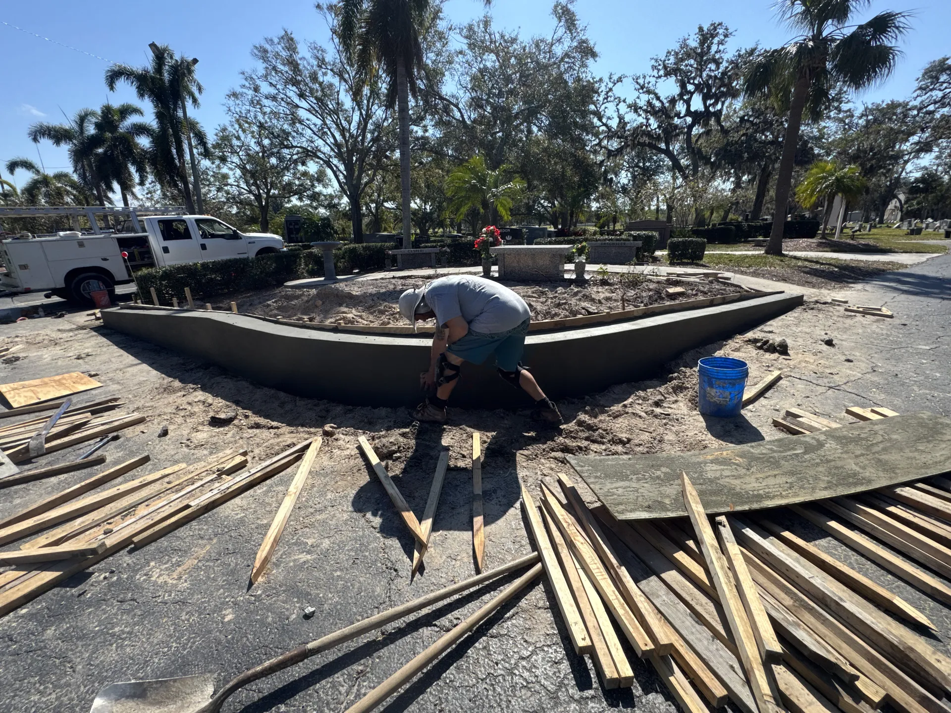 Concrete contractor finishing a curved monument sign base in a parking lot