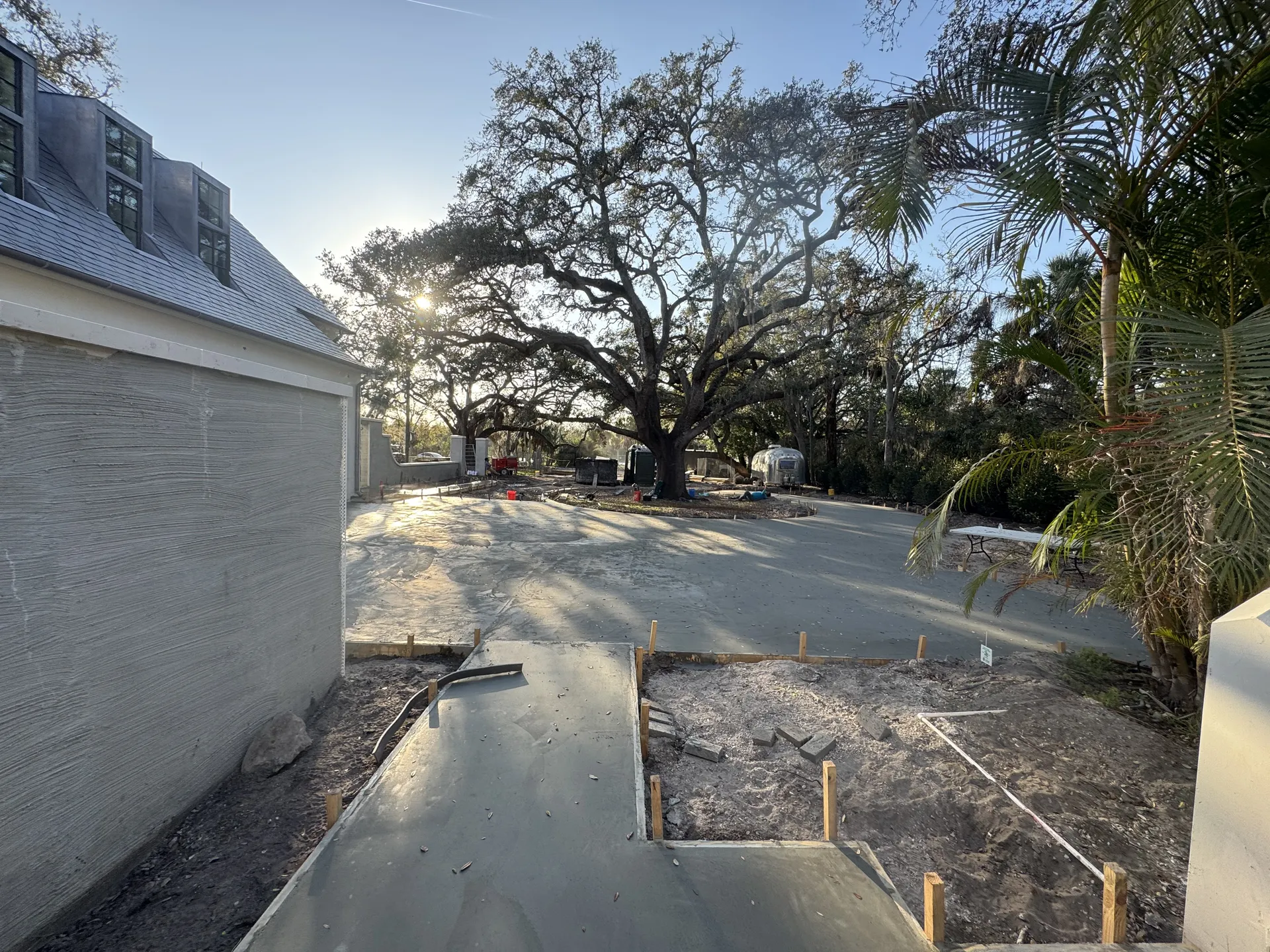 Freshly poured concrete driveway curing next to a residential property