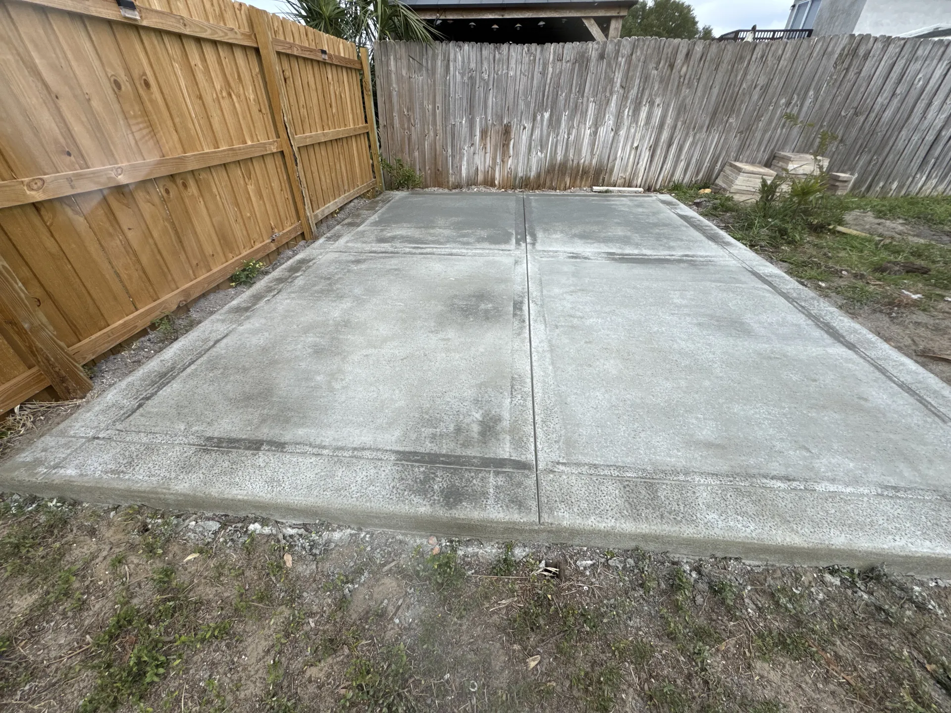 Finished concrete patio slab with control joints in a fenced backyard