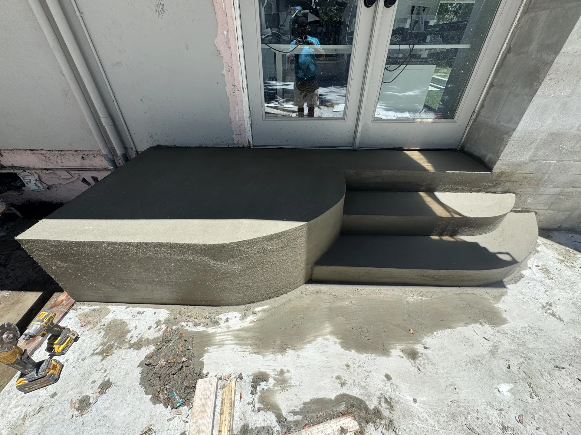 Freshly poured concrete entry steps with rounded landing at French doors