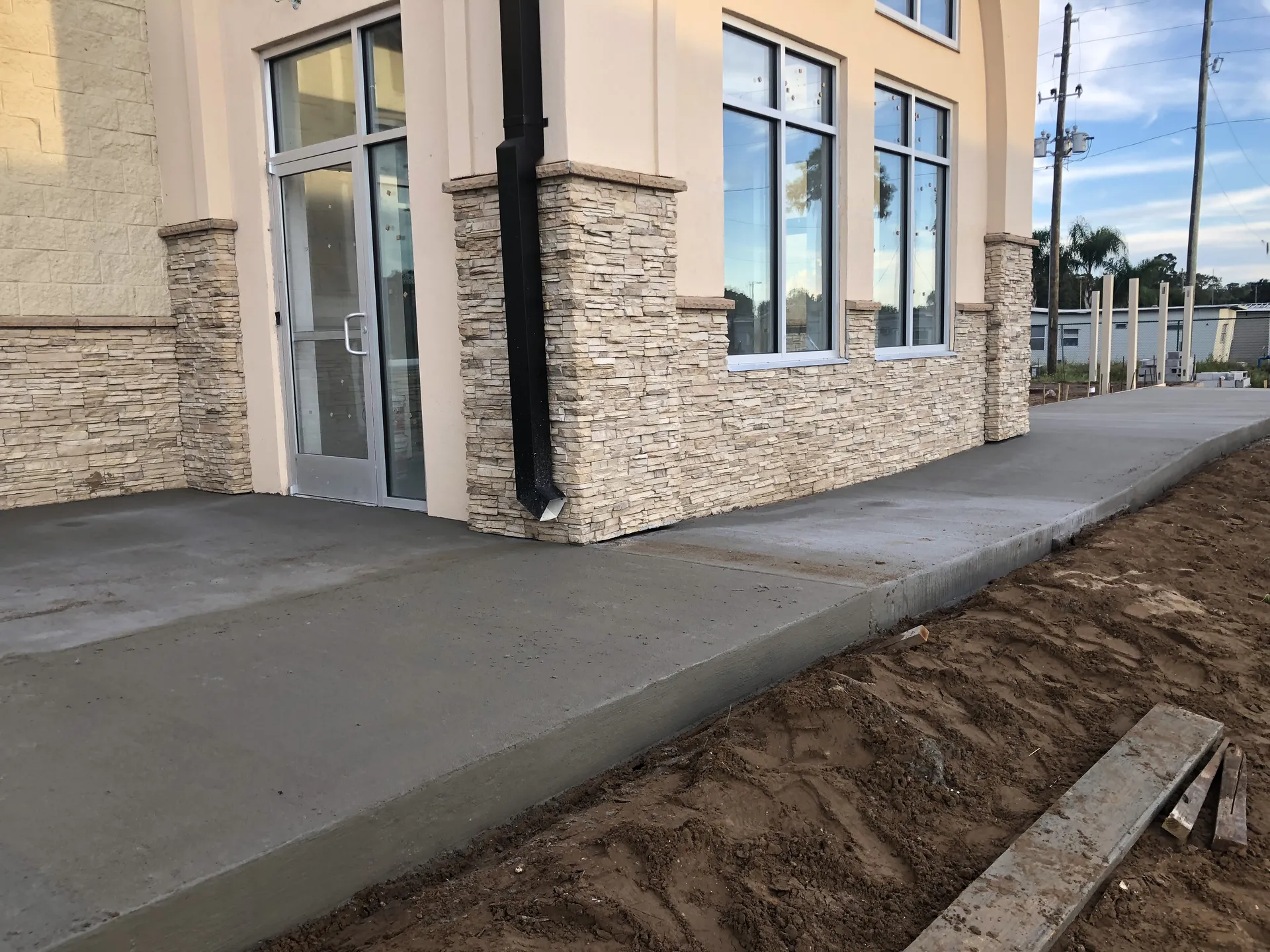 New concrete sidewalk poured along a commercial building with stone facade