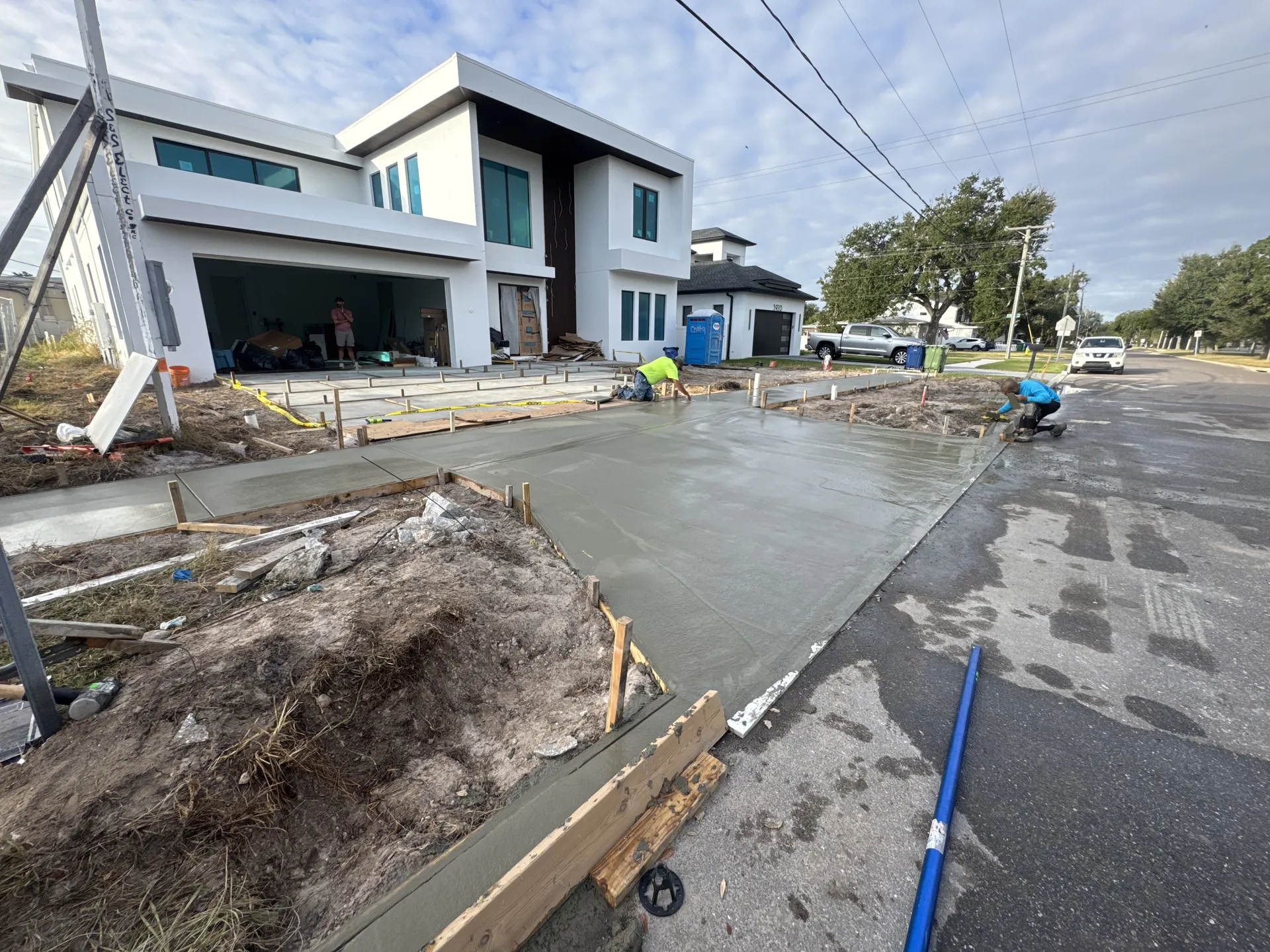 Concrete crew pouring a new driveway at a modern two-story home