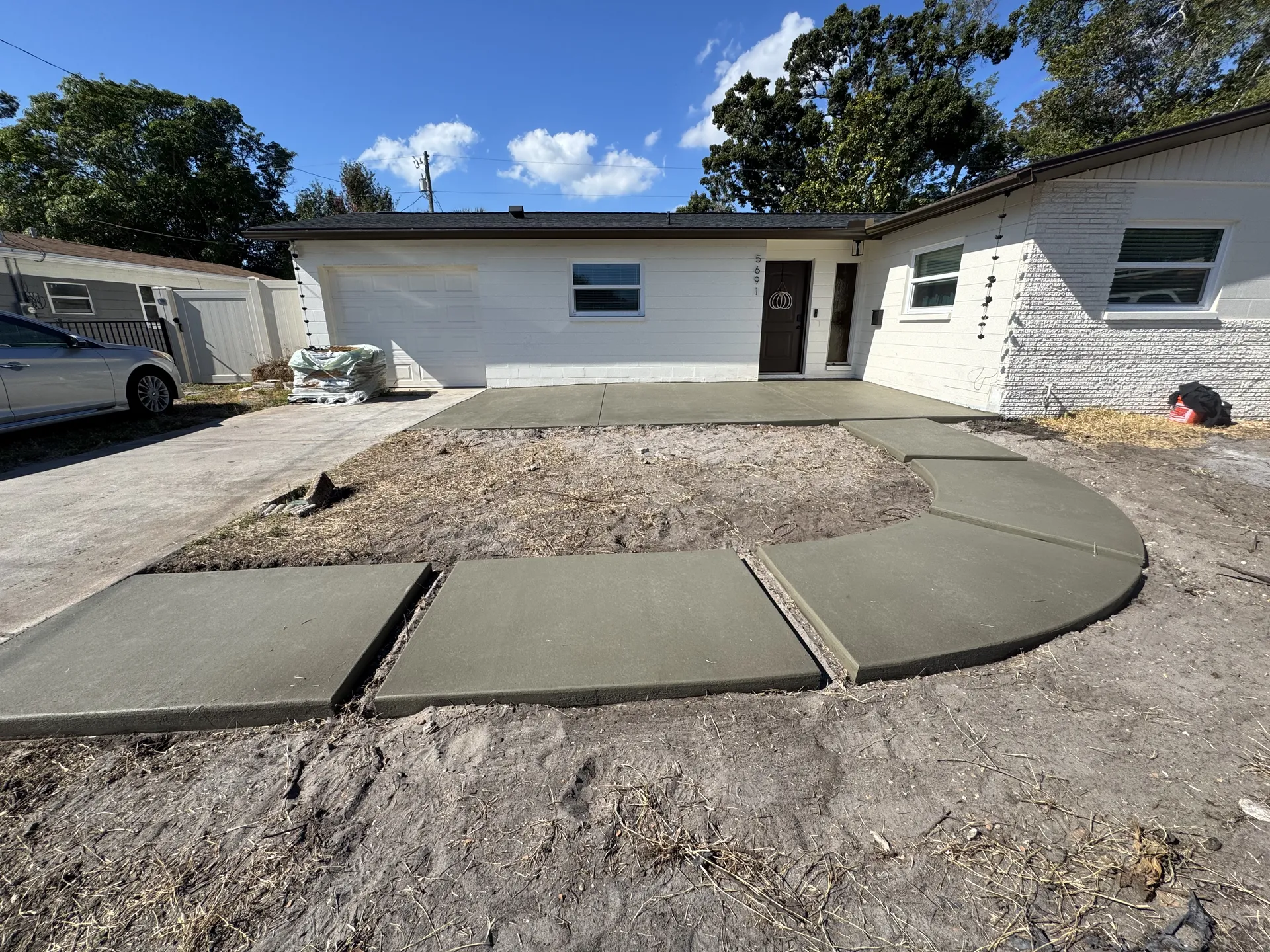 New concrete driveway and curved walkway at a residential home
