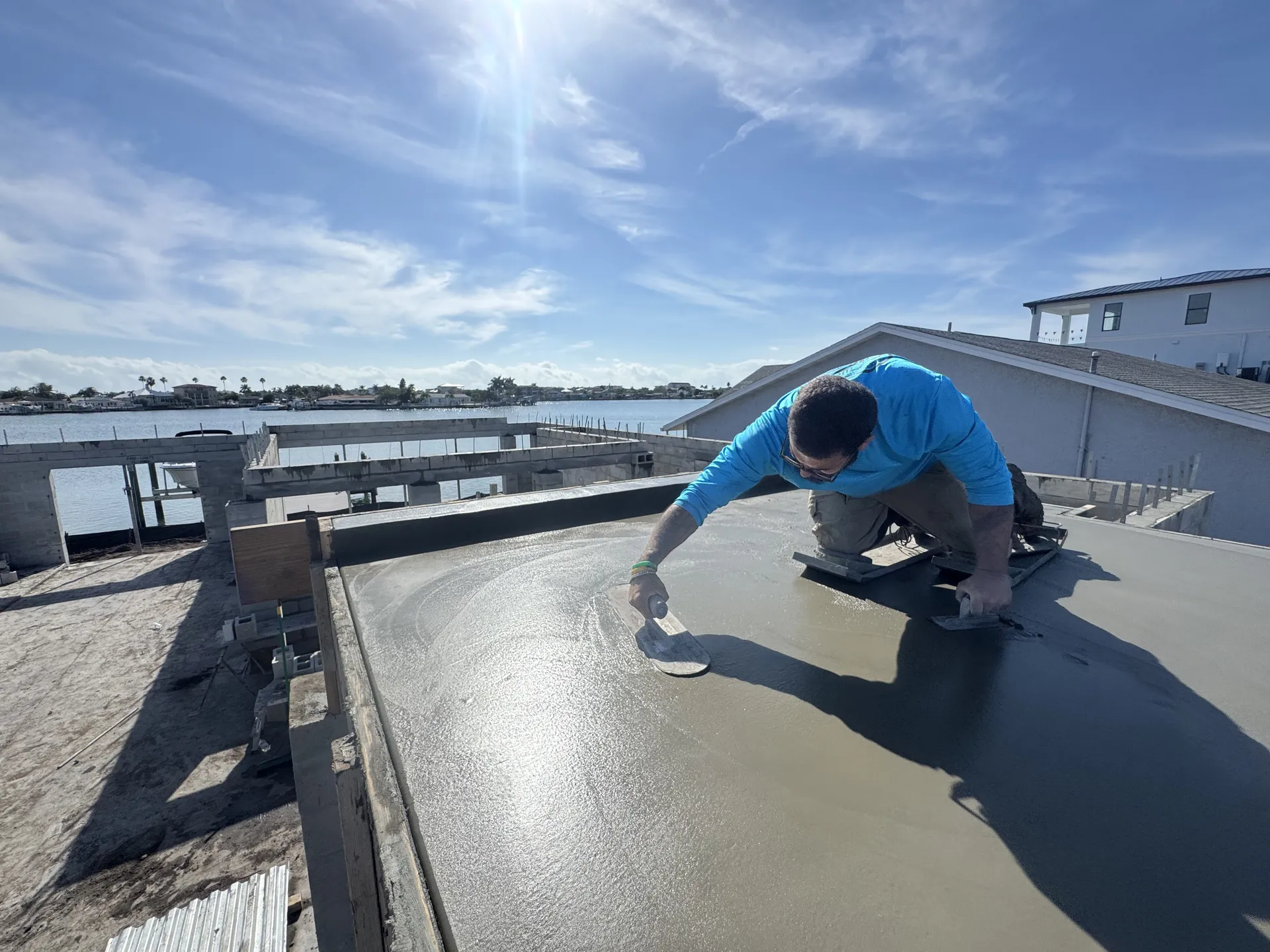 Concrete worker hand-finishing a block wall cap at a waterfront site