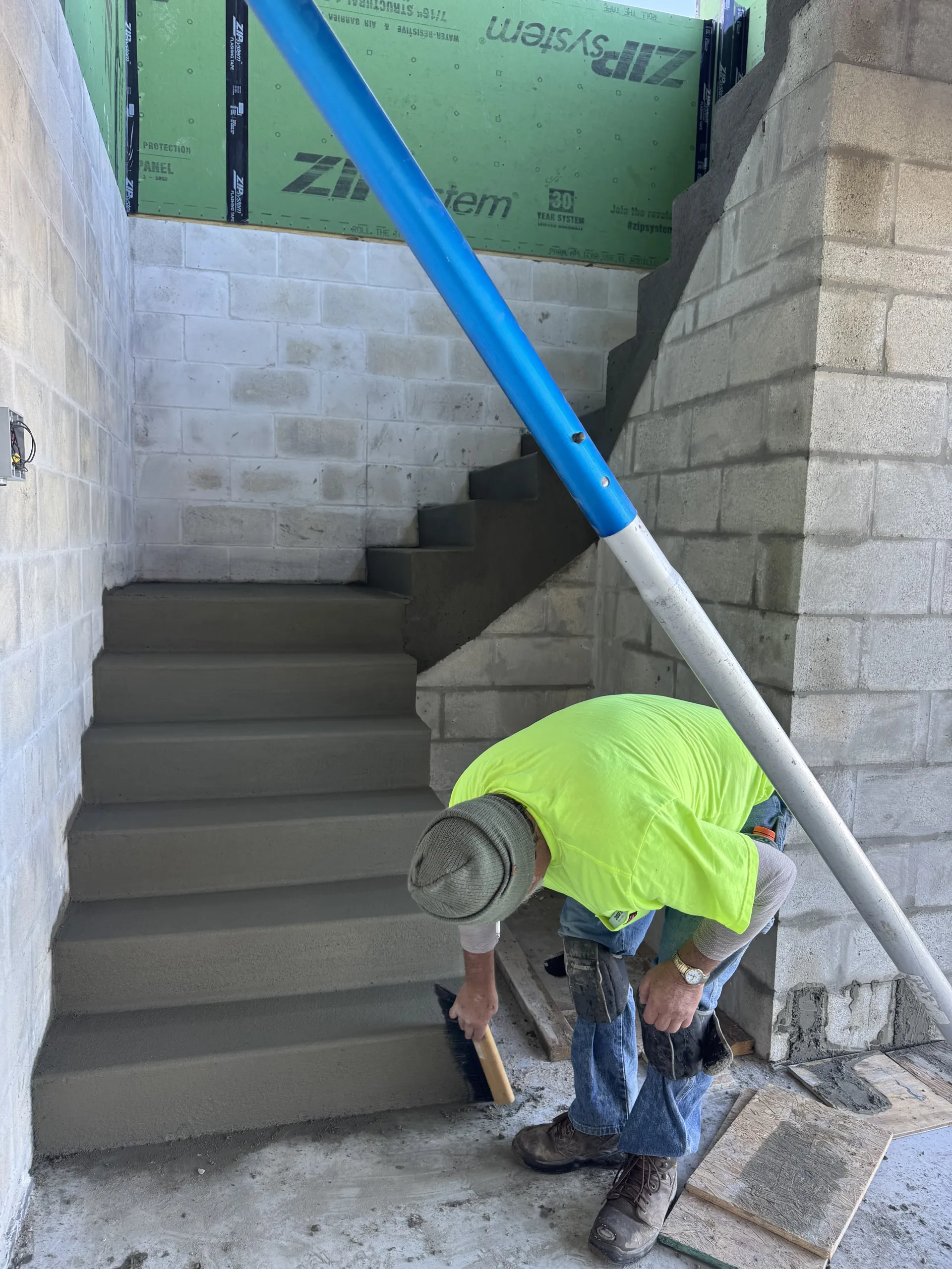 Concrete worker finishing interior stairs in a block wall stairwell
