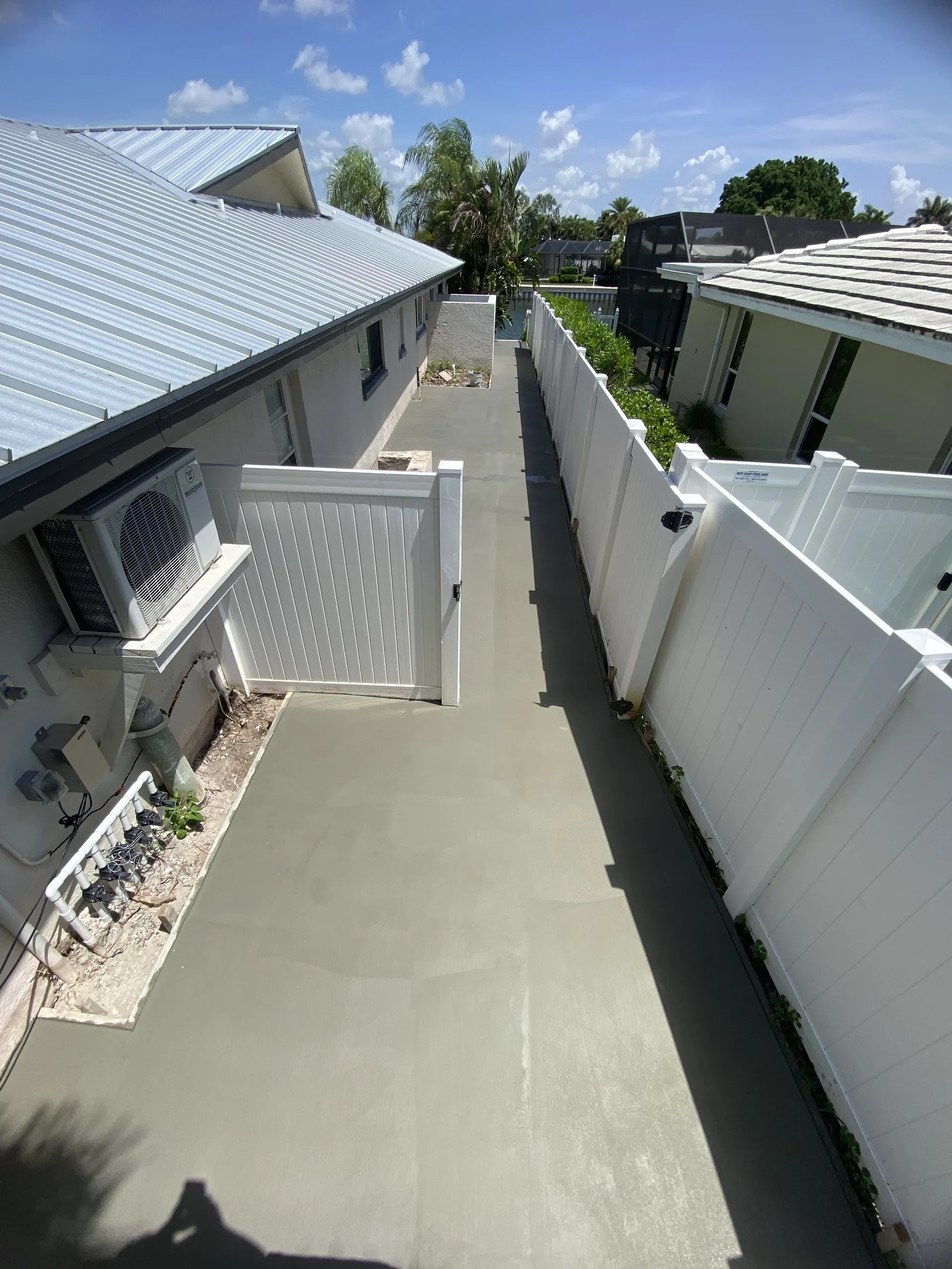 Concrete side yard walkway between buildings with vinyl privacy fencing