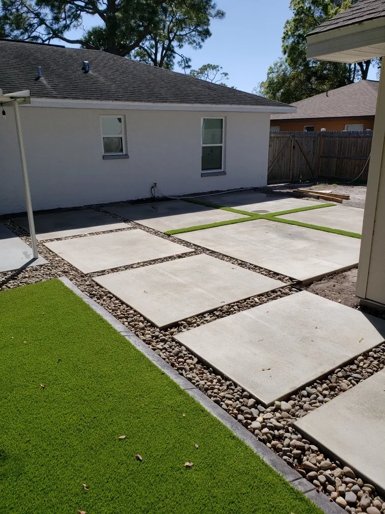 Decorative concrete patio pavers with river rock and artificial turf