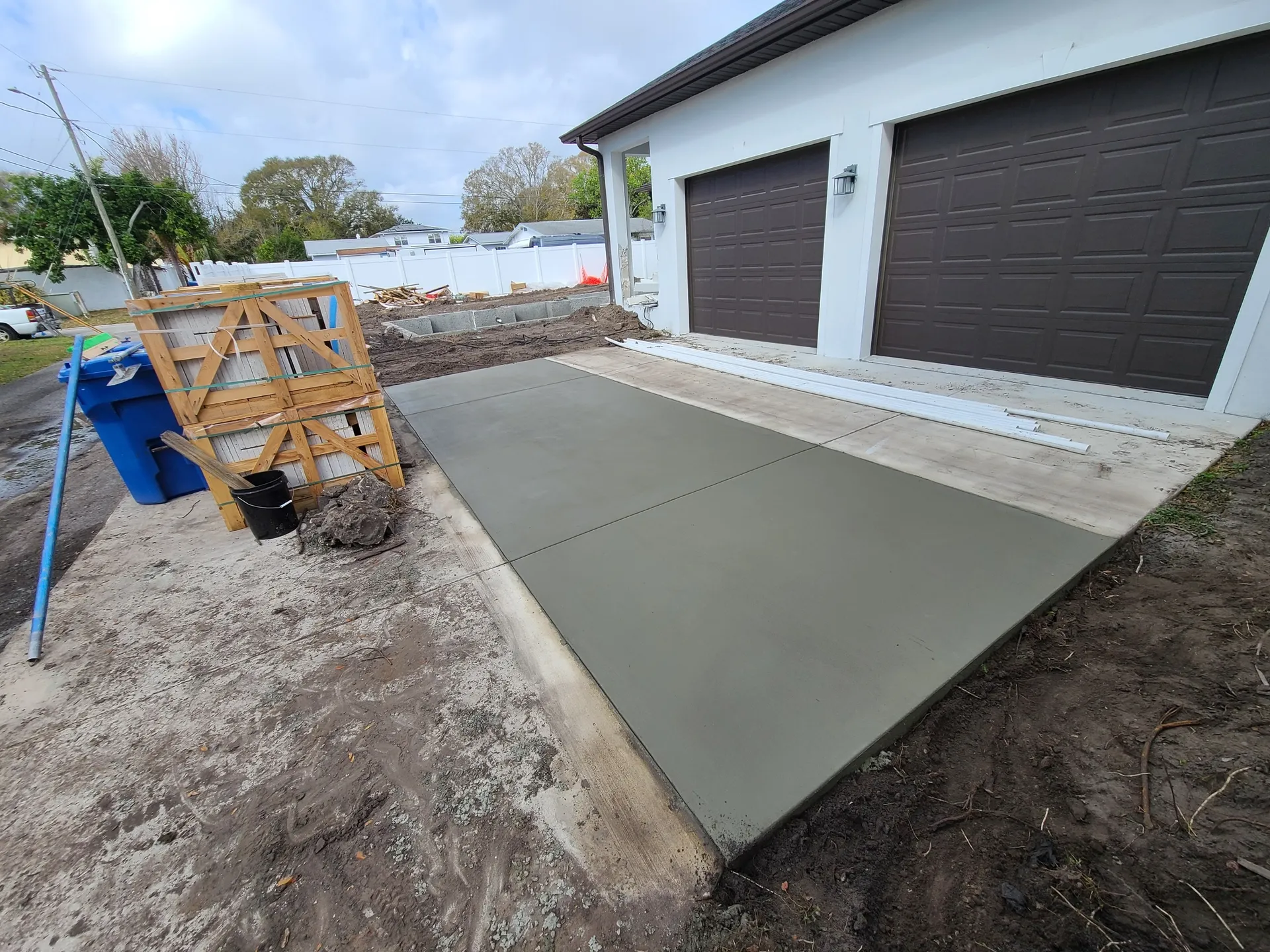 Freshly poured concrete driveway in front of a two-car garage
